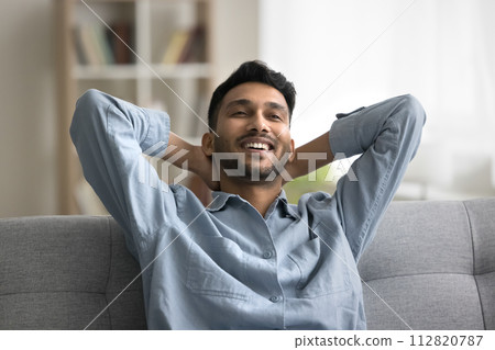 Satisfied Indian guy enjoy pleasant relaxation alone indoor 112820787