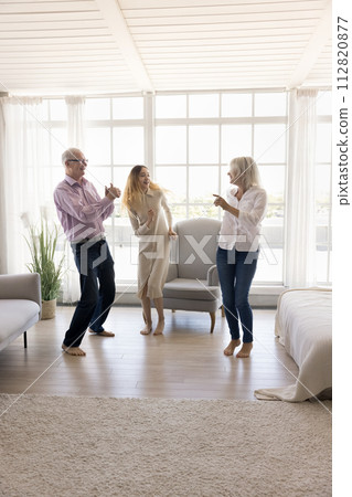 Vertical shot happy family dancing in fashionable living room 112820877