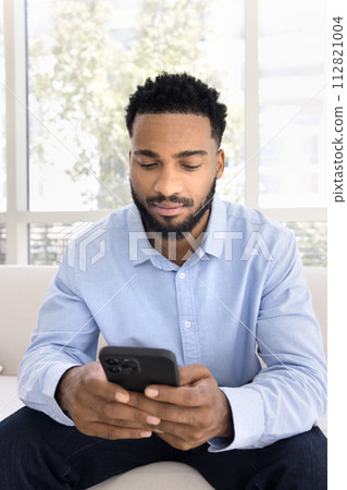 Serious young handsome Black man typing on mobile phone Serious young handsome Black man typing on mobile phone 112821004