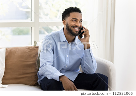 Cheerful handsome young Black business man enjoying telephone conversation Cheerful handsome young Black business man enjoying telephone conversation 112821006