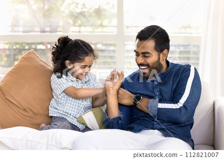 Positive Indian dad playing fight with active little daughter kid 112821007