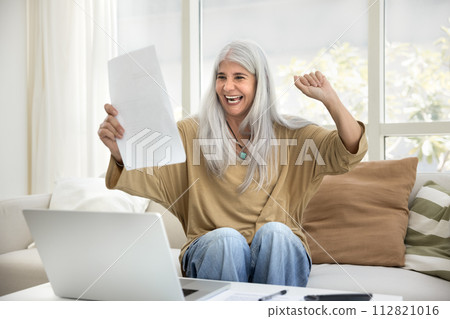 Excited cheerful senior Hispanic lady holding financial paper document Excited cheerful senior Hispanic lady holding financial paper document 112821016
