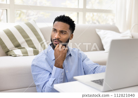 Serious thoughtful young African freelance business man working at laptop Serious thoughtful young African freelance business man working at laptop 112821040