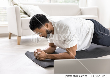 Focused strong sporty Black man training body at laptop Focused strong sporty Black man training body at laptop 112821042