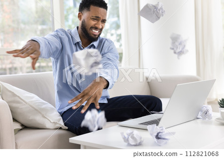 Worried nervous African freelance employee man throwing crumpled documents Worried nervous African freelance employee man throwing crumpled documents 112821068