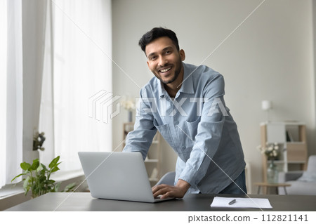 Portrait of successful Indian man posing at workplace with laptop Portrait of successful Indian man posing at workplace with laptop 112821141