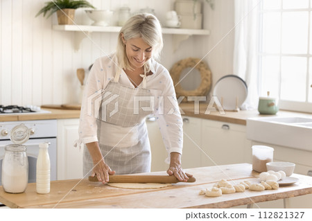 Beautiful middle-aged housewife cooking in the kitchen Beautiful middle-aged housewife cooking in the kitchen 112821327