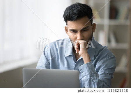 Serious man looks at laptop screen think over business concerns 112821338