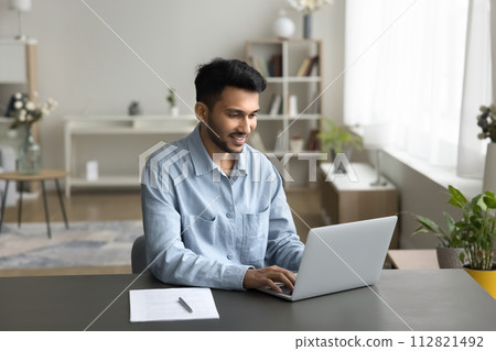 Indian businessman, freelance worker sits at desk working on-line Indian businessman, freelance worker sits at desk working on-line 112821492
