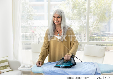 Happy cheerful older Hispanic housemaid woman doing housework Happy cheerful older Hispanic housemaid woman doing housework 112821502