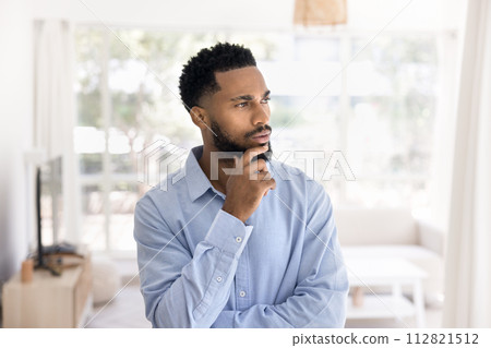 Serious pensive attractive young African man indoor portrait Serious pensive attractive young African man indoor portrait 112821512