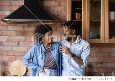 Cheerful African couple talking while standing in cozy kitchen 112821526