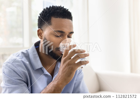 Calm thirsty young African man drinking fresh clear water Calm thirsty young African man drinking fresh clear water 112821572