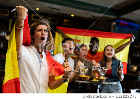 Excited man with national Spanish flag rooting for favorite team in sports bar Excited man with national Spanish flag rooting for favorite team in sports bar 112822775