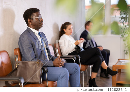 Adult man in business suit sits in line at reception Adult man in business suit sits in line at reception 112822841