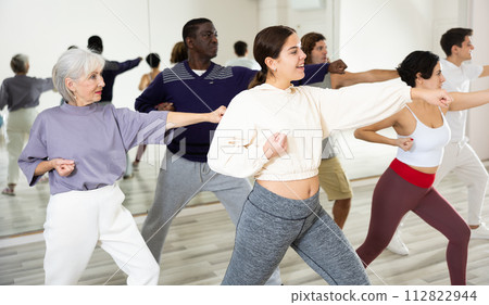 Cheerful young lady learning new modern dance in group dance lesson 112822944
