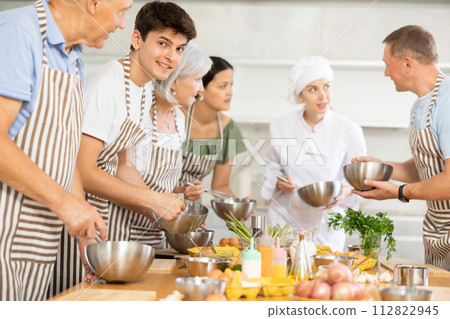 Cooking class - happy friends cooking and talking in kitchen Cooking class - happy friends cooking and talking in kitchen 112822945