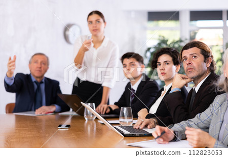 Focused colleagues of different ages discussing ideas and watching presentation while gathering in meeting room Focused colleagues of different ages discussing ideas and watching presentation while gathering in meeting room 112823053