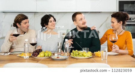 Two married couples are sitting at table, enjoying food and wine, chatting, talking, laughing. Two married couples are sitting at table, enjoying food and wine, chatting, talking, laughing. 112823059