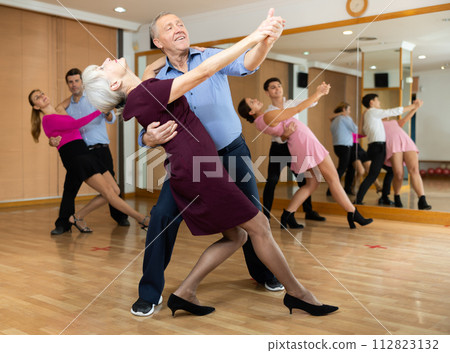 Couple of mature dancers rehearsing ballroom dances in dance studio Couple of mature dancers rehearsing ballroom dances in dance studio 112823132