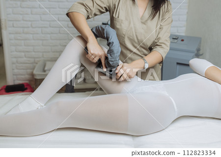 Beautiful woman getting beauty therapy against cellulite with LPG machine on her butt. LPG massage for lifting body. Beautiful woman getting beauty therapy against cellulite with LPG machine on her butt. LPG massage for lifting body. 112823334