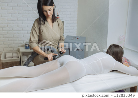 Woman in special white suit getting anti cellulite massage in a spa salon. LPG, and body contouring treatment in clinic.Reset body weight with LPG massage 112823349