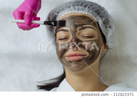 Close-up of carbon peeling procedure for middle-aged woman face. Laser pulses clean skin. Process of photothermolysis, warming, laser carbon peeling. Facial skin rejuvenation, cosmetology treatment. Close-up of carbon peeling procedure for middle-aged woman face. Laser pulses clean skin. Process of photothermolysis, warming, laser carbon peeling. Facial skin rejuvenation, cosmetology treatment. 112823371