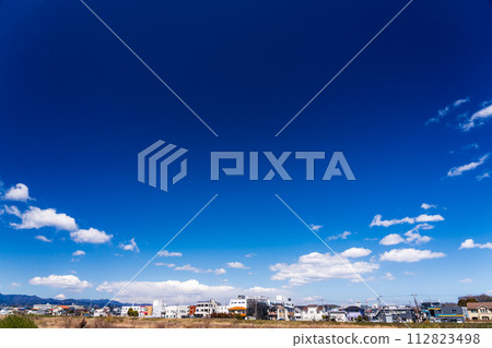 白雲飄浮在春天的藍天和住宅區 白雲飄浮在春天的藍天和住宅區 112823498