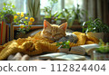 A serene scene with a ginger cat peacefully napping on a vibrant yellow knitted blanket, with houseplants and books in a sunlit room. 112824404