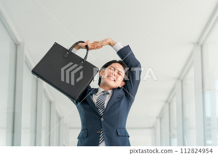 A young Asian male businessman in a suit stretching after work (overwork/overtime) A young Asian male businessman in a suit stretching after work (overwork/overtime) 112824954