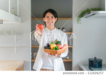 A man holding vegetables in his home kitchen (organic/pesticide-free vegetables/dietary fiber/macrobiotics/diet) 112826257