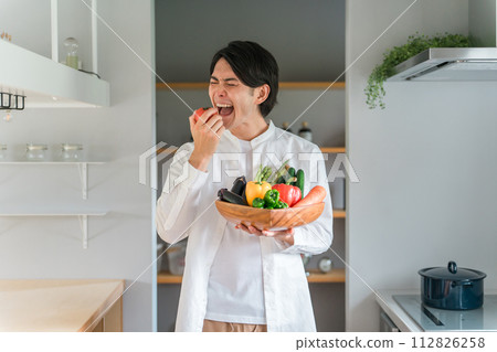 A man holding vegetables in his home kitchen (organic/pesticide-free vegetables/dietary fiber/macrobiotics/diet) A man holding vegetables in his home kitchen (organic/pesticide-free vegetables/dietary fiber/macrobiotics/diet) 112826258