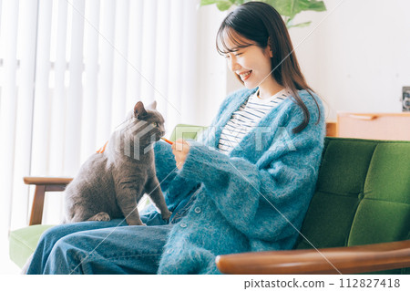 A woman giving a treat to a cat 112827418