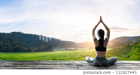 Asian woman doing yoga on the wooden balcony Asian woman doing yoga on the wooden balcony 112827443
