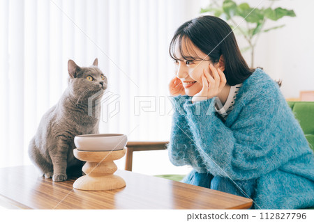 A woman feeding a cat 112827796