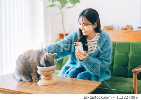 A woman petting a cat eating food A woman petting a cat eating food 112827889