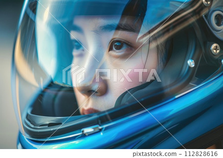 Close-up portrait of an Asian woman gazing through a blue visor of a safety motorcycle helmet Close-up portrait of an Asian woman gazing through a blue visor of a safety motorcycle helmet 112828616