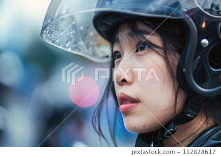 Close-up portrait of an Asian woman gazing through a blue visor of a safety motorcycle helmet 112828617