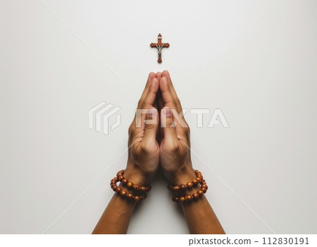 Soulful prayer: a man in quiet devotion, hands clasped around a rosary cross, seeking solace and spiritual connection, capturing the essence of serene contemplation, faith, and religious devotion. 112830191