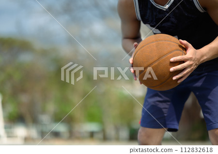 Cropped shot of sportsman dribbling the ball on an outdoor court. People, sport and active lifestyle concept Cropped shot of sportsman dribbling the ball on an outdoor court. People, sport and active lifestyle concept 112832618