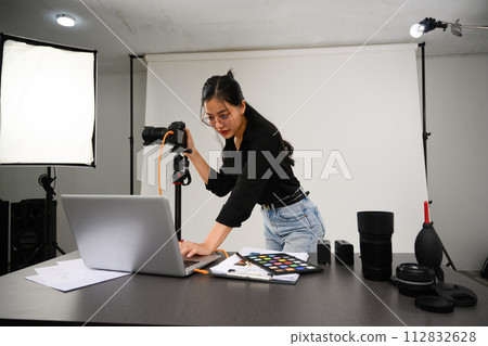 Portrait of female photographer with professional camera working in modern studio Portrait of female photographer with professional camera working in modern studio 112832628