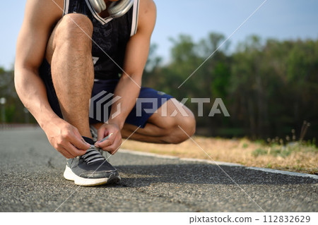 Sportsman tying shoelace getting ready for jogging or cardio workout. Healthy lifestyle concept Sportsman tying shoelace getting ready for jogging or cardio workout. Healthy lifestyle concept 112832629