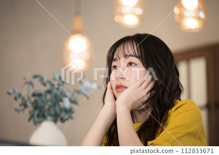 晚上在房間裡靠著下巴的年輕女人 112833671