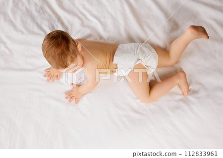 Cute little baby boy, child in diaper lying on bed, crawling, playing isolated over white studio background 112833961