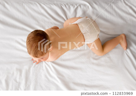 Beautiful little baby boy in diaper lying on bed, crawling, playing isolated over white studio background 112833969