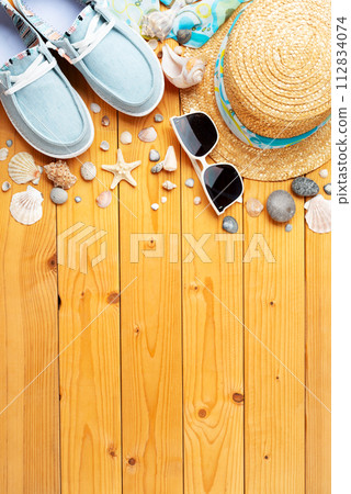 Holiday vacation travel planning background of straw hat, sunglasses, moccasins and shells on natural wood planks Holiday vacation travel planning background of straw hat, sunglasses, moccasins and shells on natural wood planks 112834074