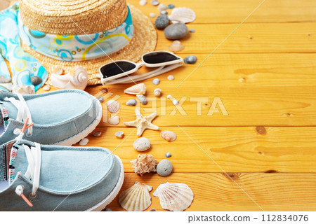 Holiday vacation travel planning background of straw hat, sunglasses, moccasins and shells on natural wood planks Holiday vacation travel planning background of straw hat, sunglasses, moccasins and shells on natural wood planks 112834076