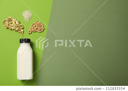 Bottle with alternative milk and herbal ingredients on green background, space for text Bottle with alternative milk and herbal ingredients on green background, space for text 112835554