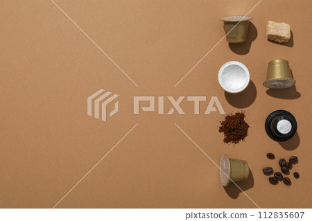 Coffee capsules and beans, sugar on brown background, space for text Coffee capsules and beans, sugar on brown background, space for text 112835607