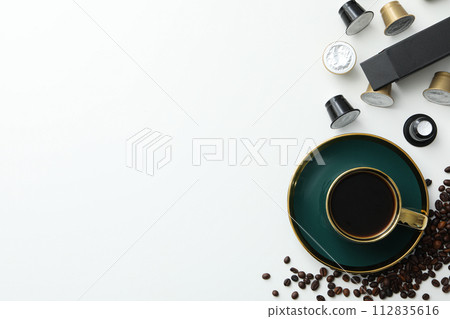 Coffee capsules and beans, cup with coffee drink on white background, space for text 112835616